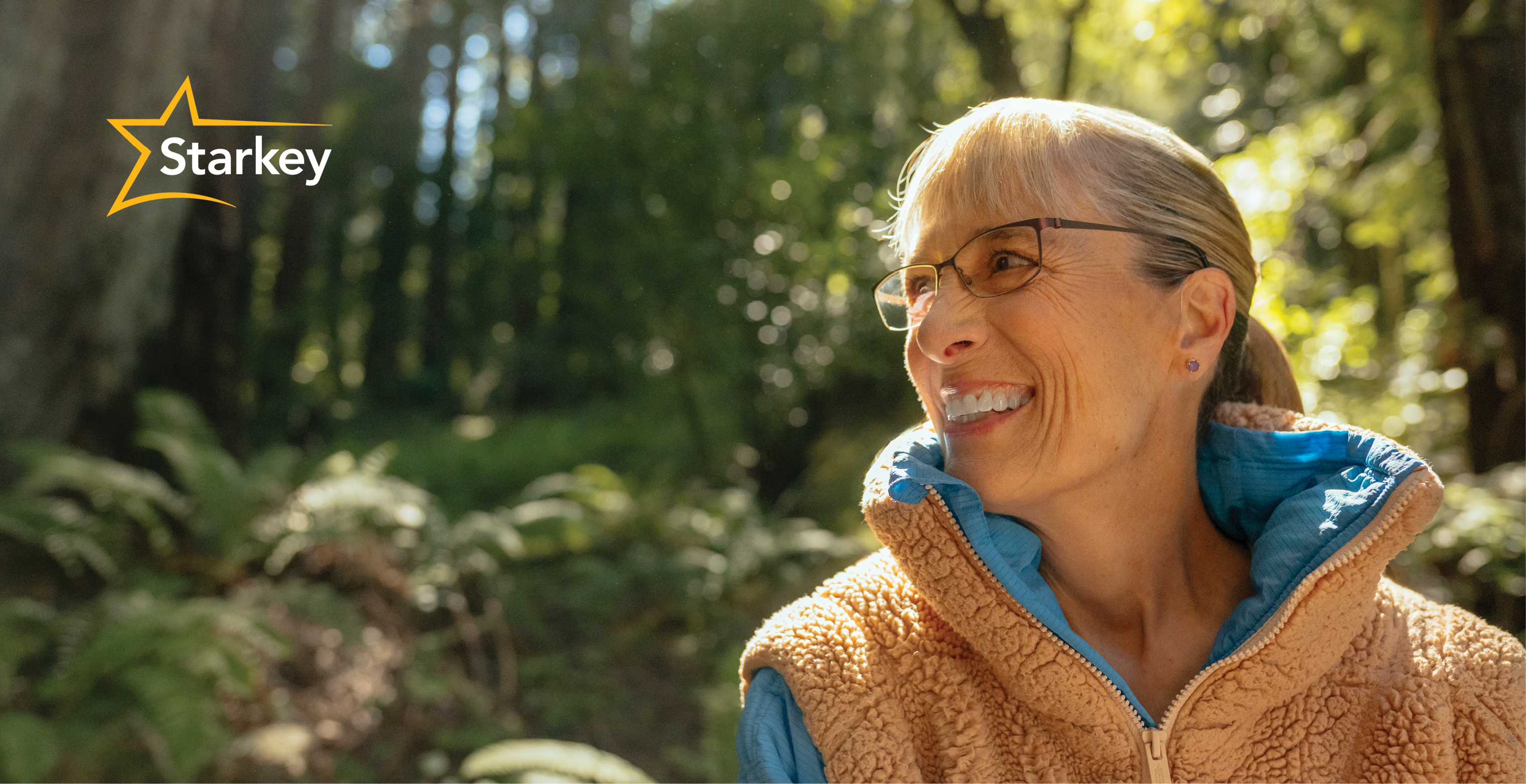 Image of middle aged woman in the forest looking to the side and smiling